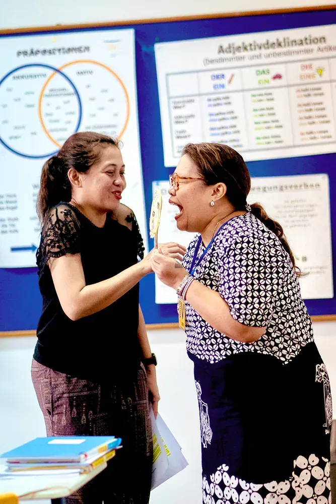 Two women standing next to each other in front of a bulletin board