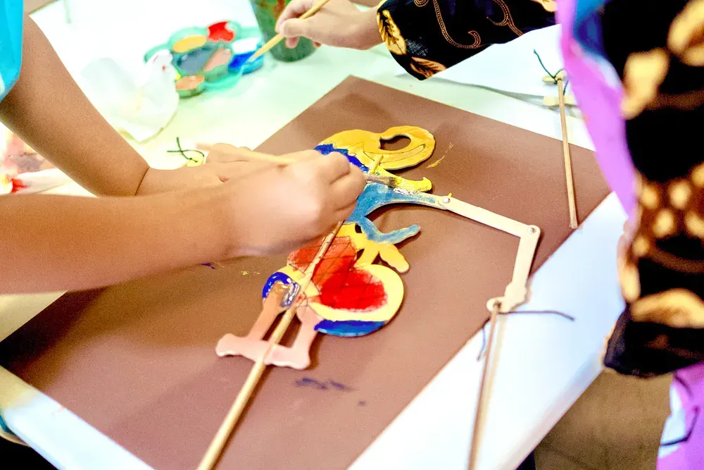 A person is painting a puppet on a piece of paper