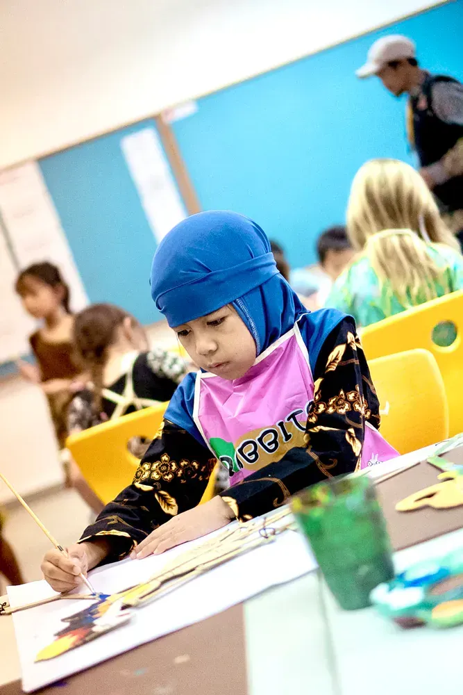 A little girl wearing a pink apron with the word rabbit on it