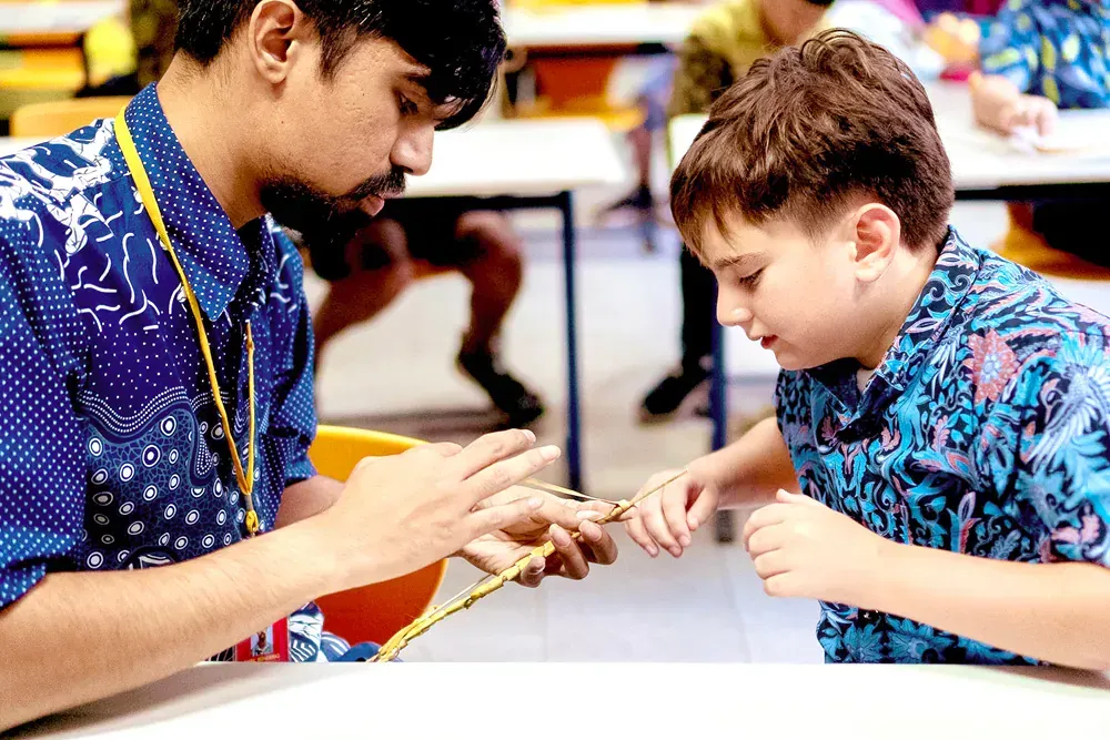 A man and a boy are sitting at a table in a classroom.