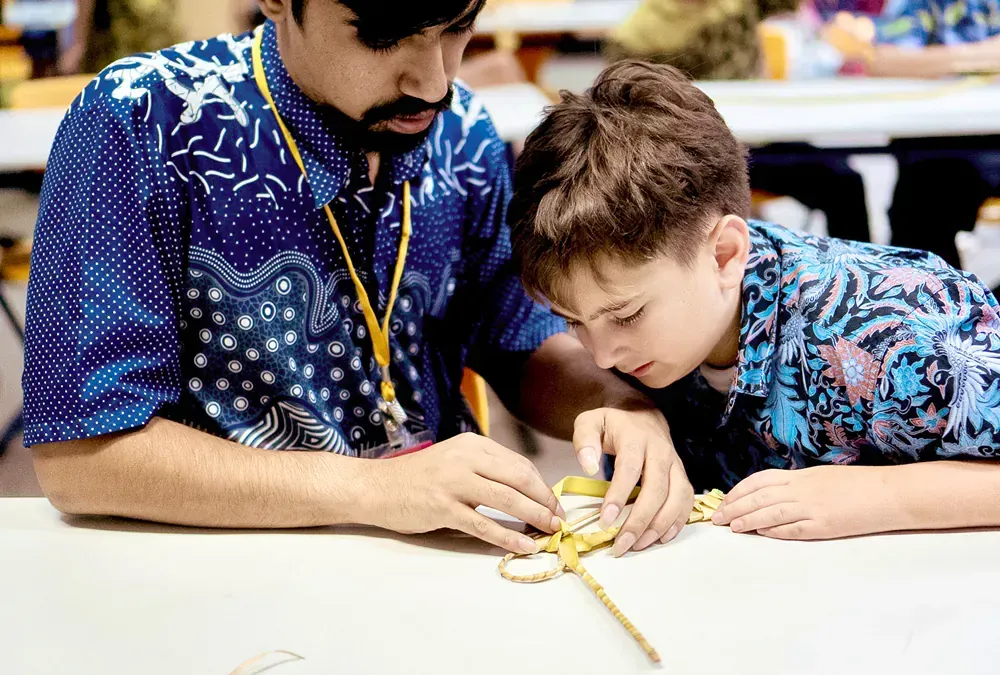 A man and a boy are sitting at a table working on a project.
