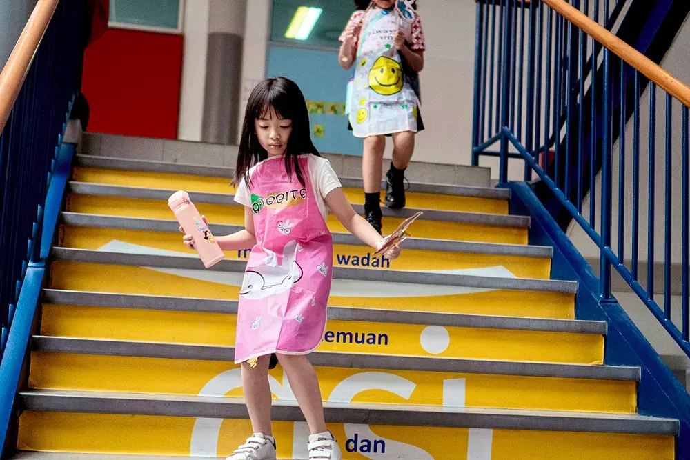 Two little girls are walking up a set of stairs.