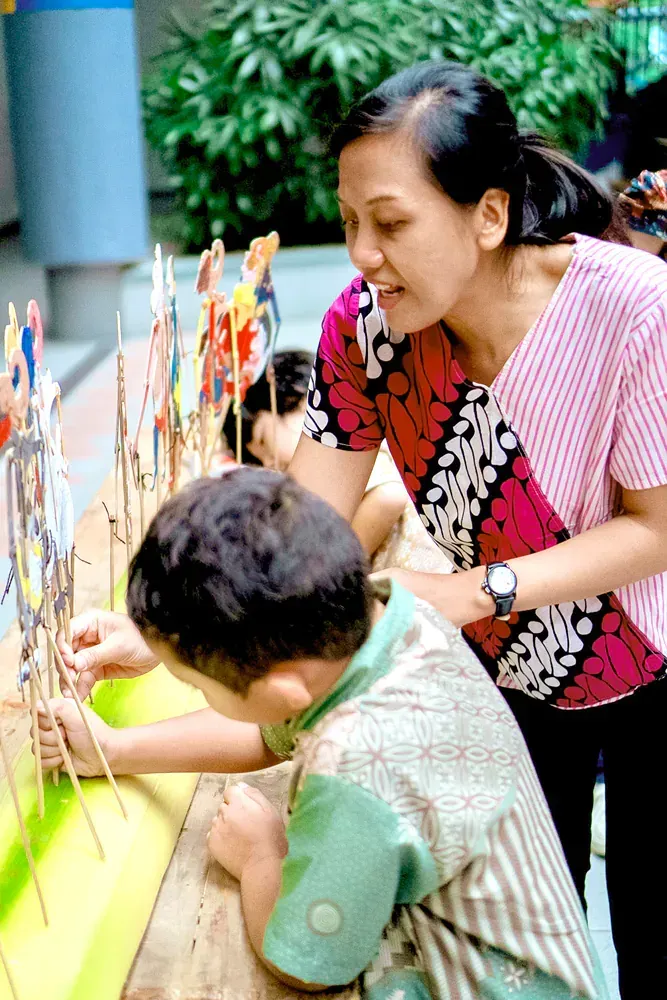 A woman and a child are looking at a display of paper dolls.