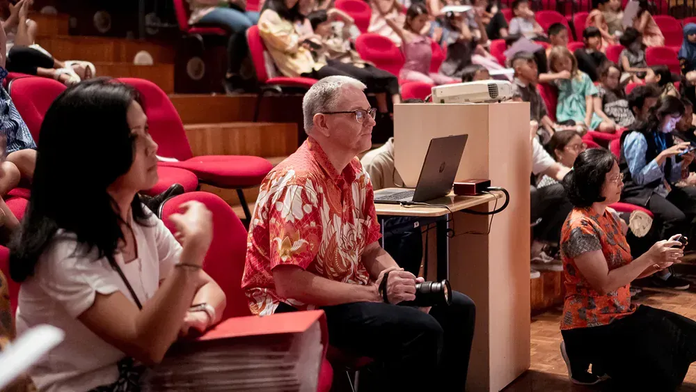 A group of people are sitting in an auditorium watching a presentation.