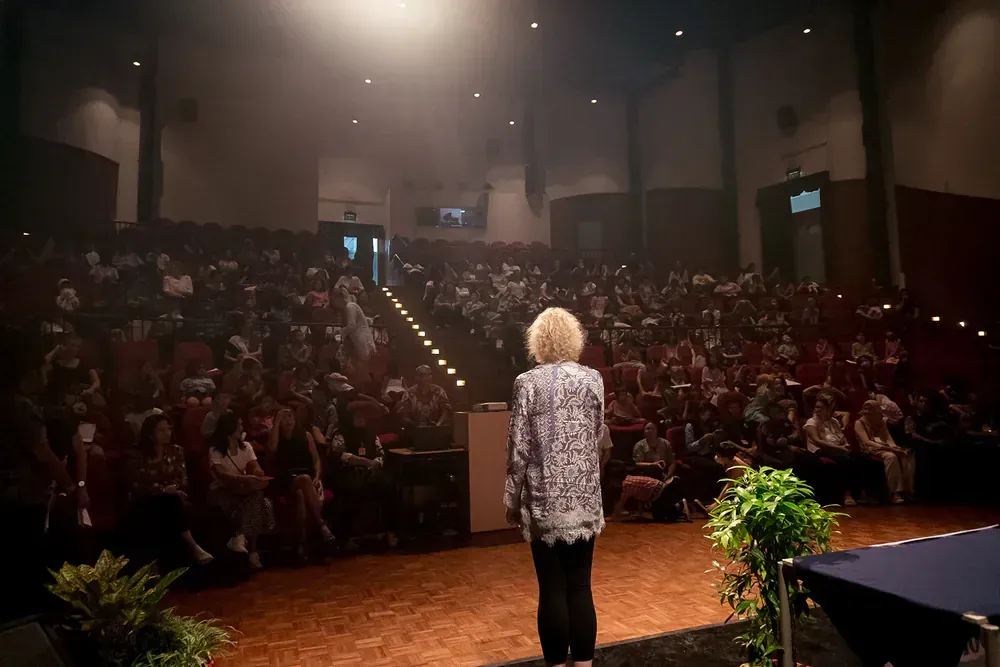 A woman is standing on a stage in front of a crowd.