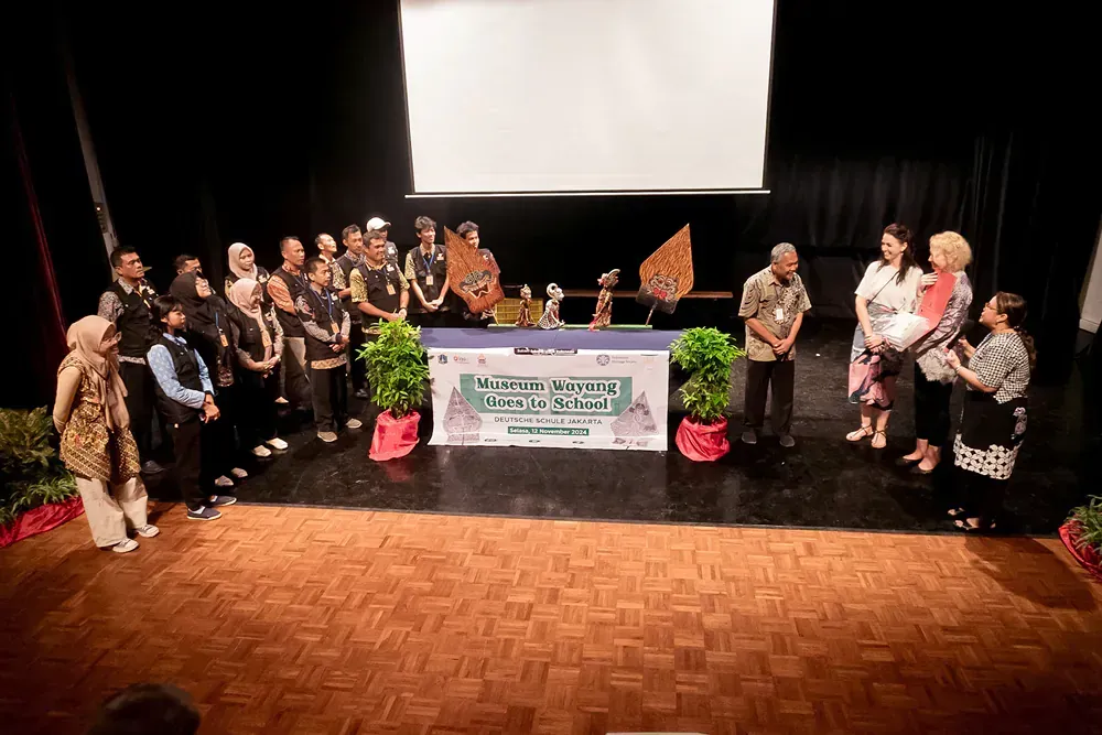 A group of people are standing on a stage in front of a large screen.