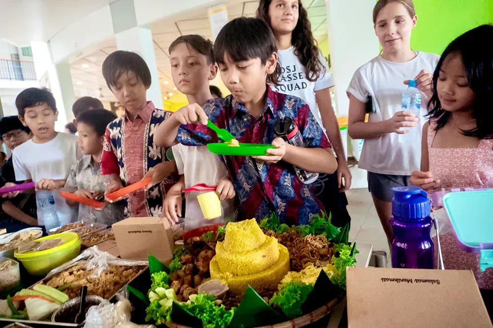 A group of children are standing around a table eating food.