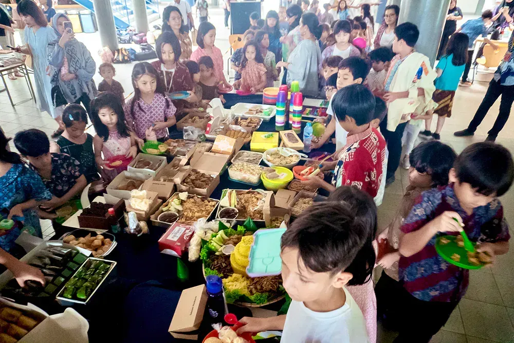 A group of children are standing around a table eating food.