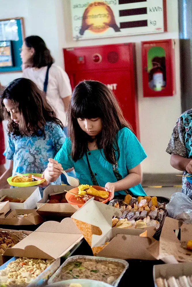 A group of children are sitting at a table eating food.