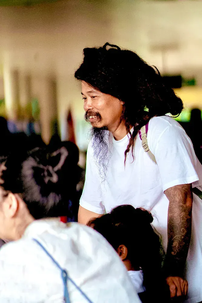 A man with dreadlocks and a mustache wearing a white shirt