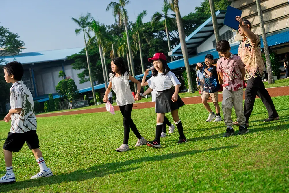 A group of children are walking on a lush green field.