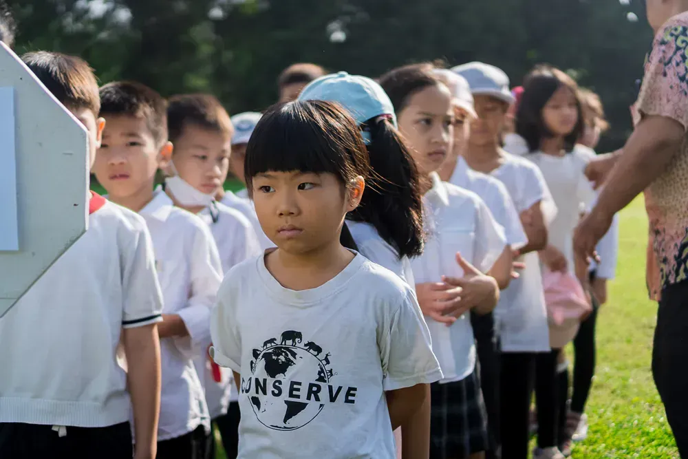 A group of children are standing in a line in a field.