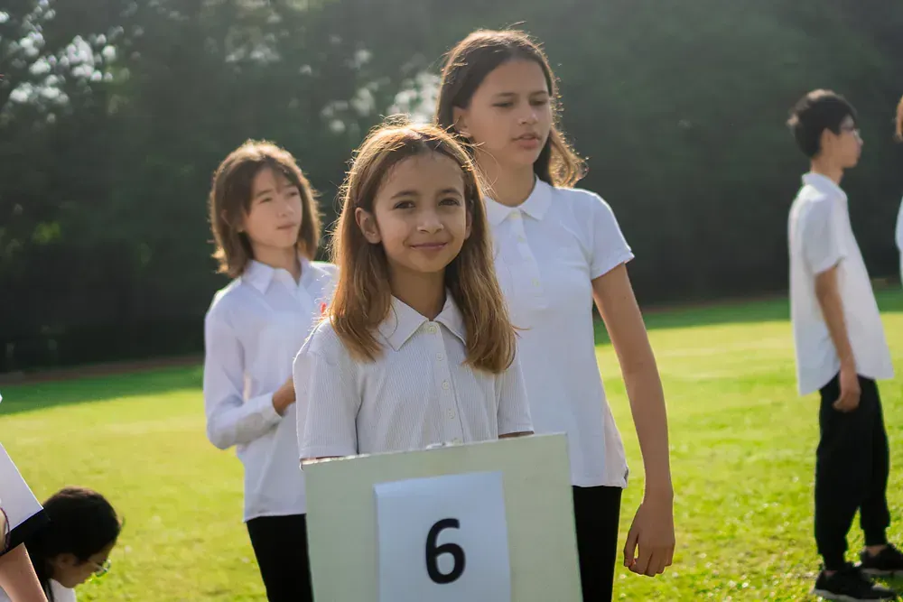 A group of young girls are standing in a line on a field holding a sign with the number 6 on it.