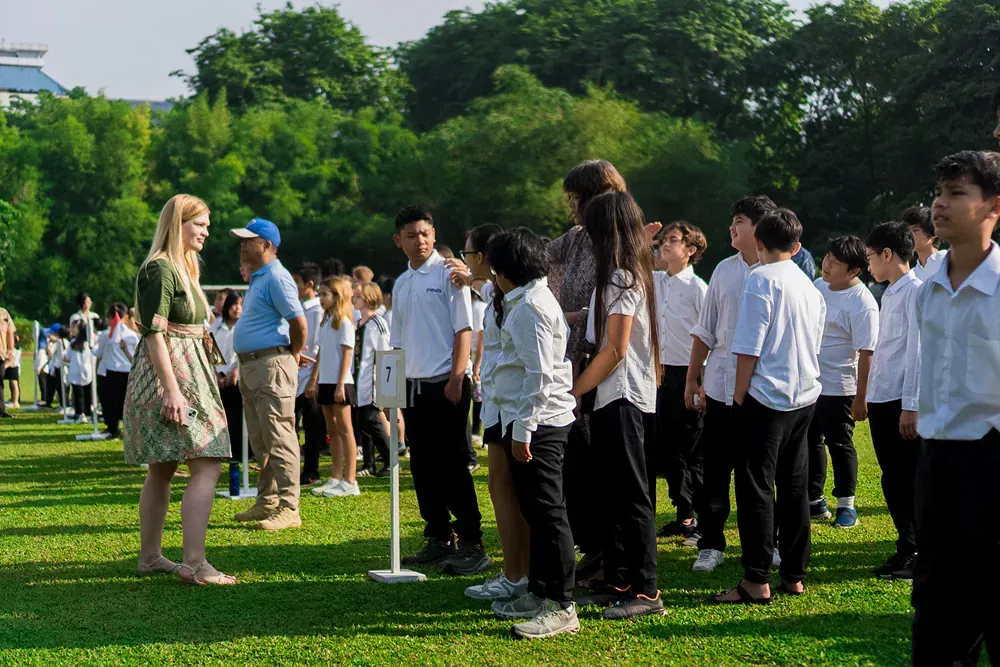 A group of children are standing on top of a lush green field.