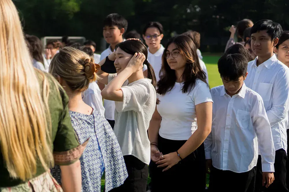 A group of young people are standing in a line in a park.