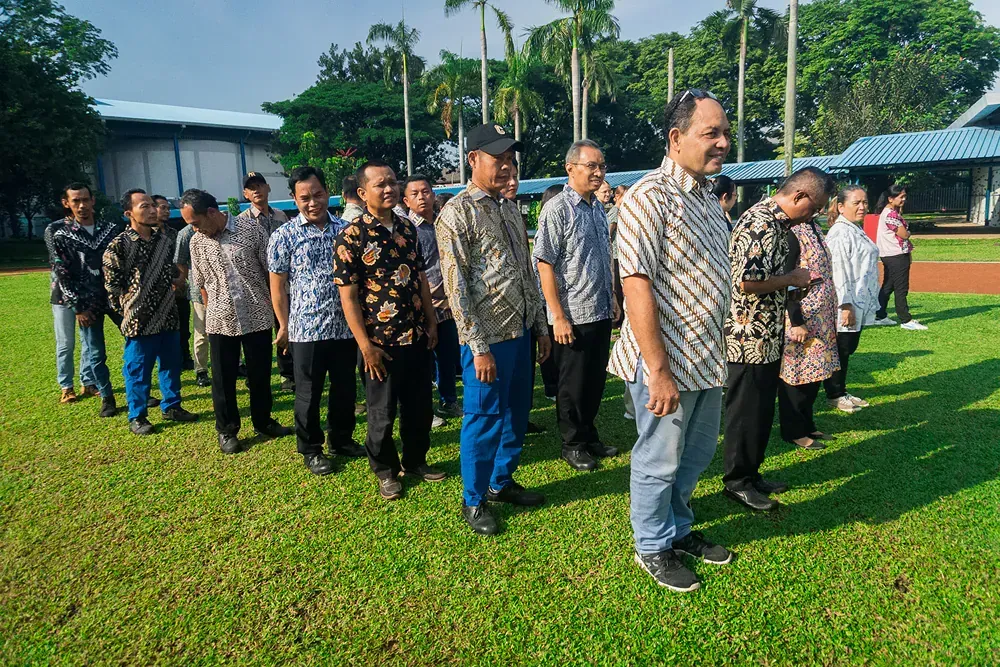 A group of men are standing in a line on a lush green field.