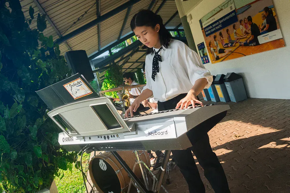 A young girl is playing a keyboard in a room.
