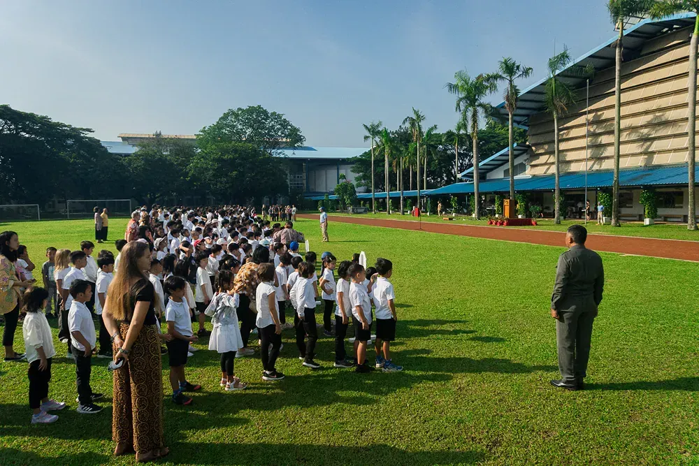 A large group of children are standing in a grassy field.