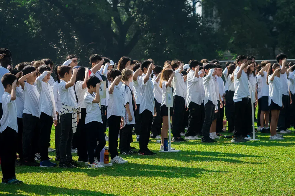 A large group of people are saluting in a field.