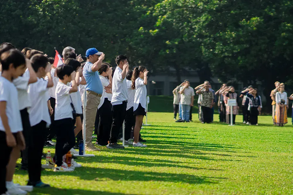 A group of people are standing on top of a lush green field.