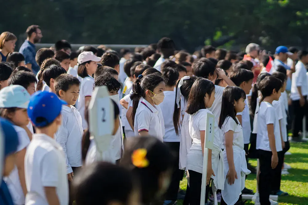A large group of children are standing in a line on a field.