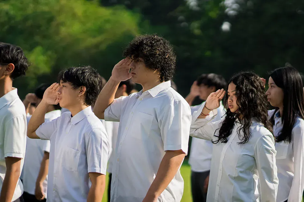 A group of young people are saluting in a park.