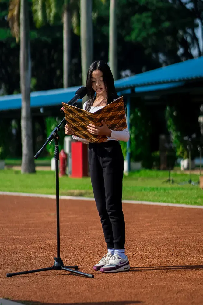 A woman is standing in front of a microphone reading a book.