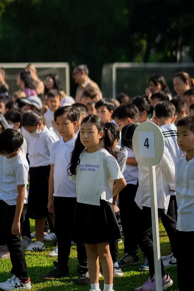 A group of children are standing in a line on a field.