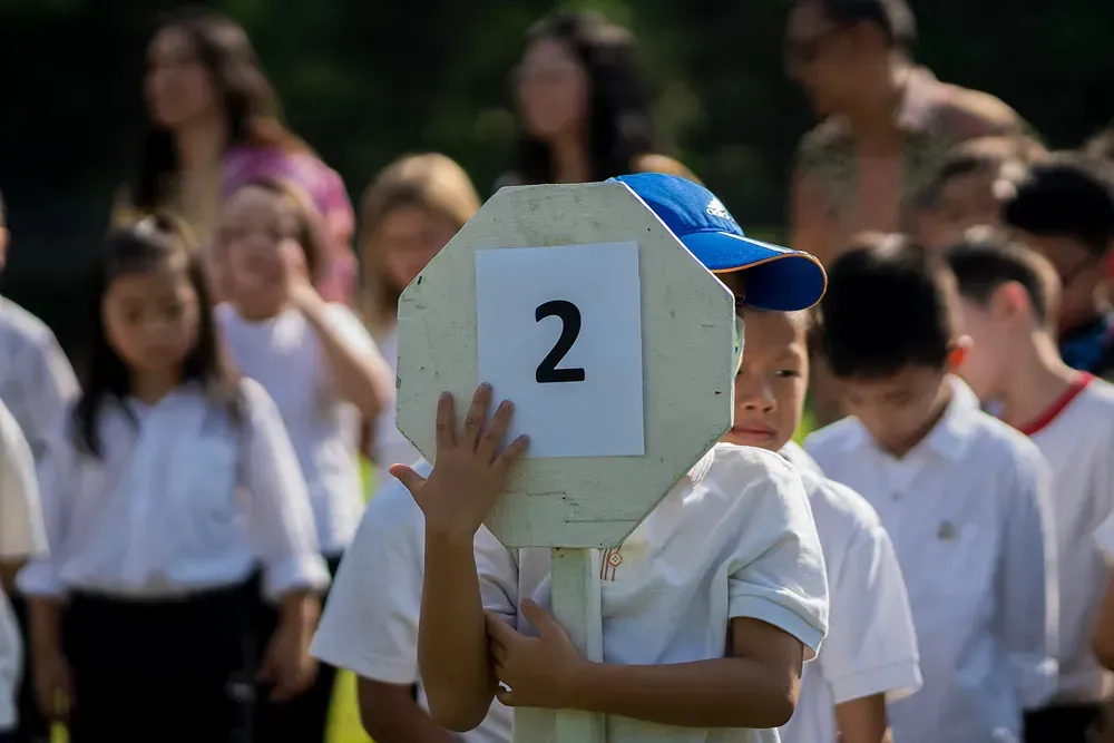 A young boy is holding a stop sign with the number 2 on it.