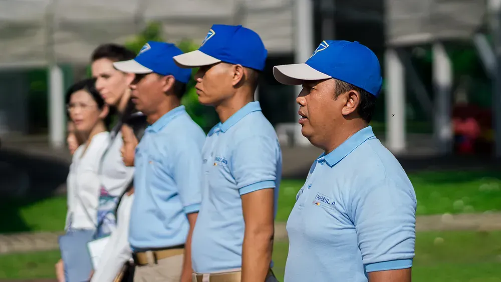 A group of men in blue shirts and blue hats are standing in a line.