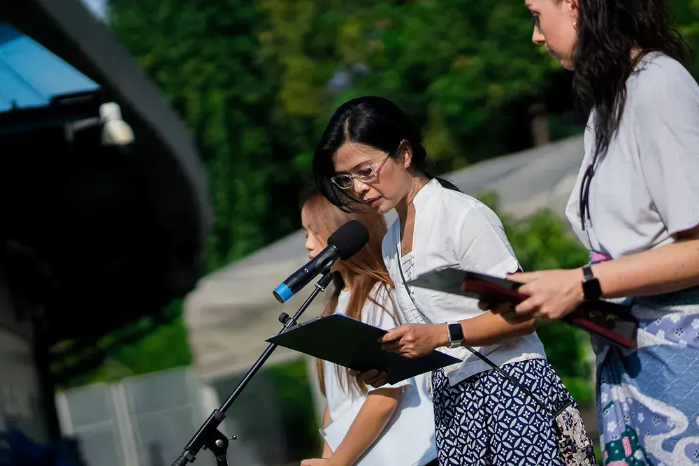 A group of women are standing in front of a microphone.