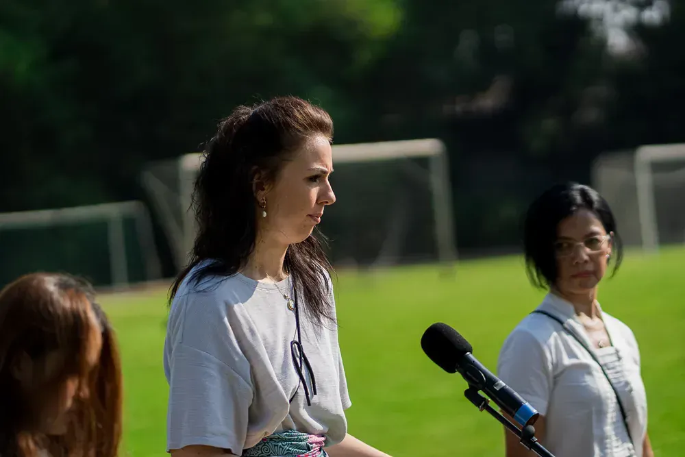 A woman is standing in front of a microphone on a field.