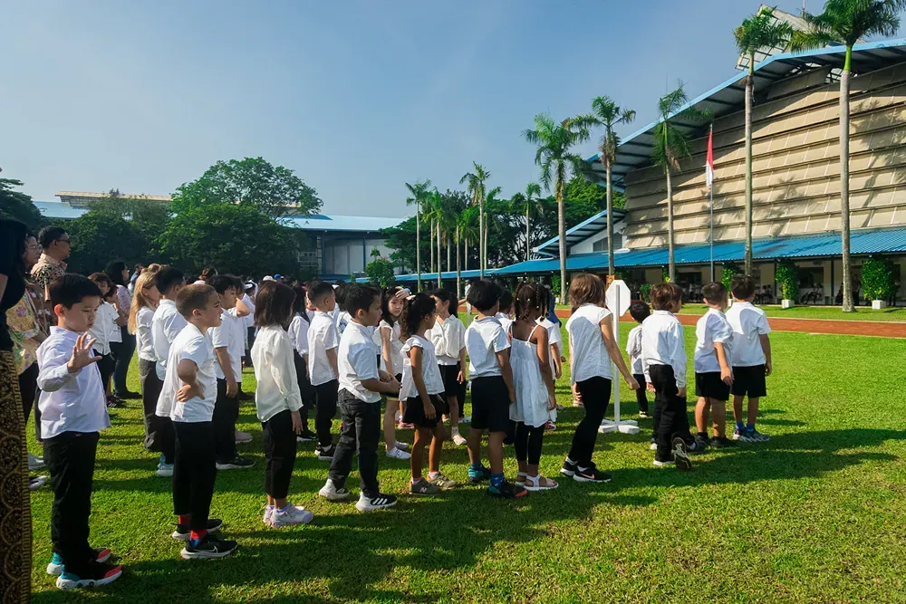 A group of children are standing in a grassy field.