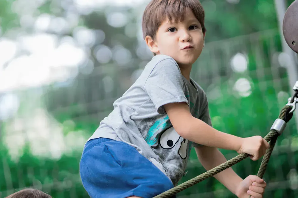A young boy is playing with a rope in a park.