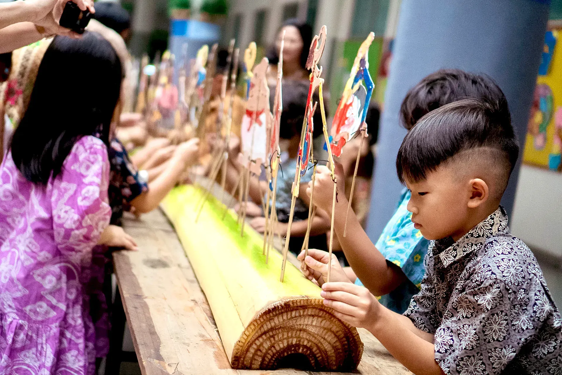 A group of children are playing with sticks on a wooden table.