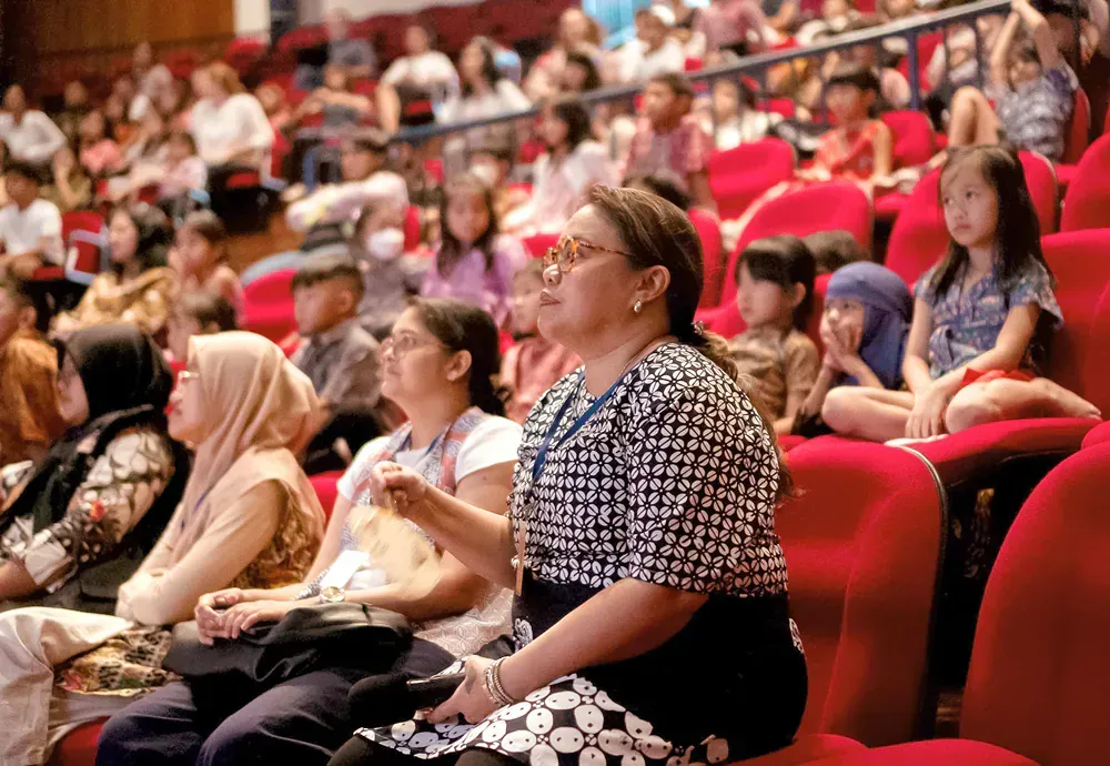 A woman is sitting in the audience of a theater.