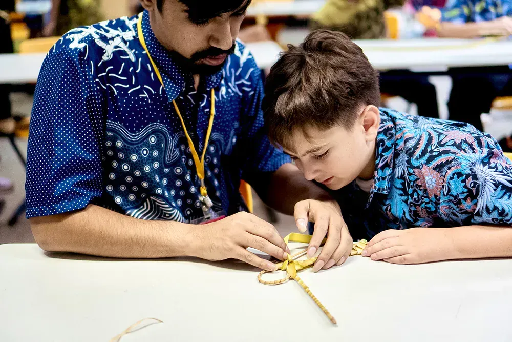 A man and a boy are sitting at a table working on a project.