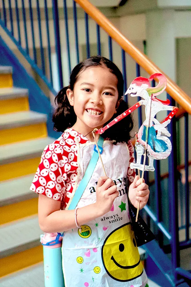 A little girl is standing on a set of stairs holding a lantern.