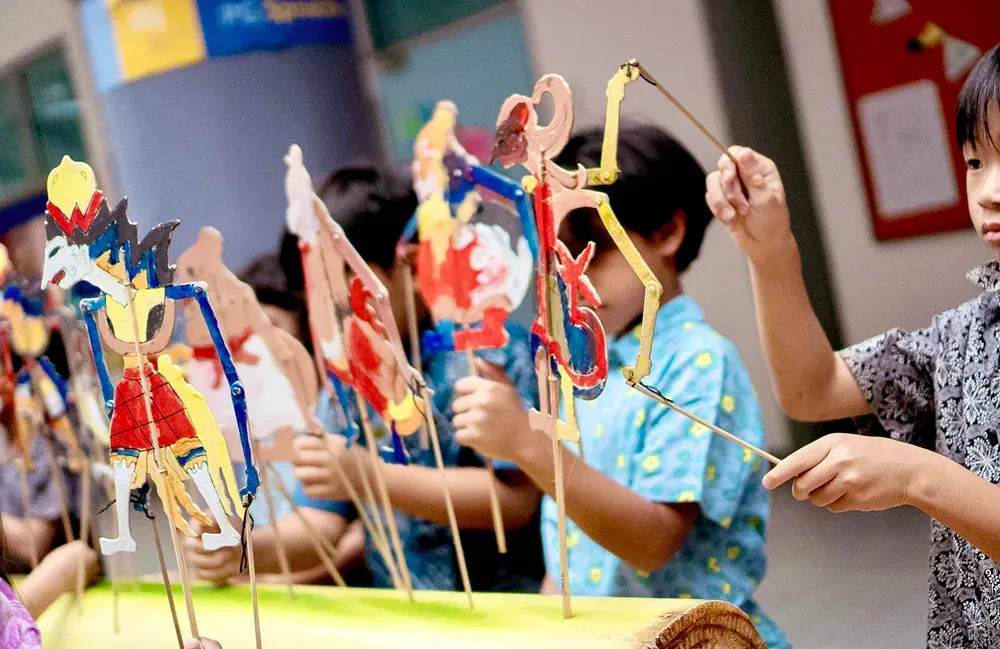 A group of children are playing with paper puppets.