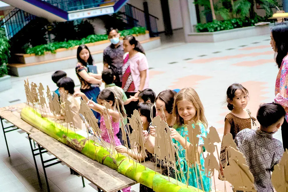 A group of children are standing around a table with cardboard figures on it.