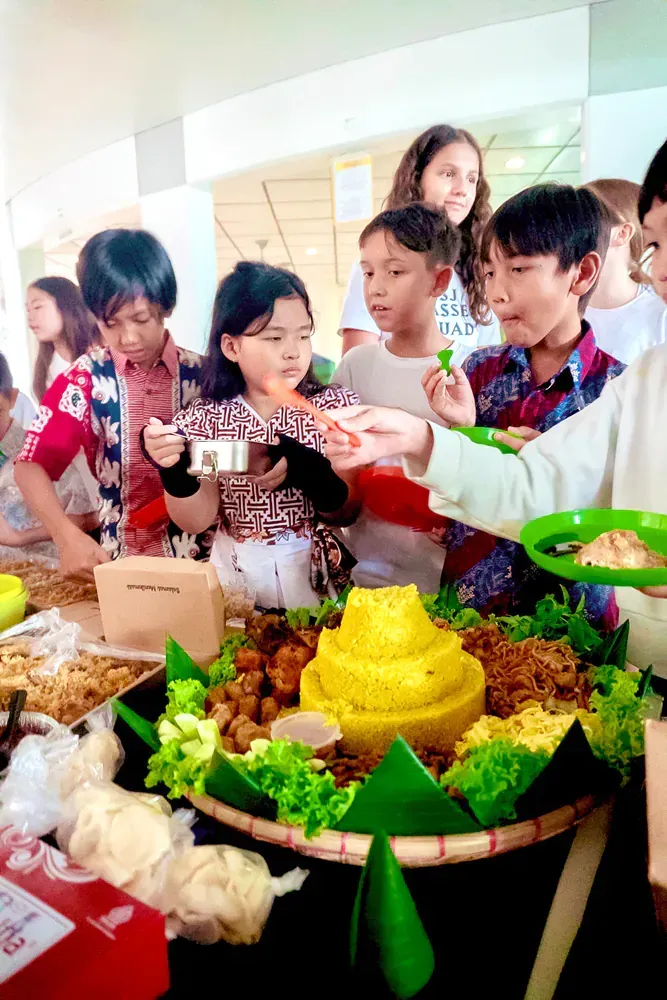 A group of children are standing around a table with food.