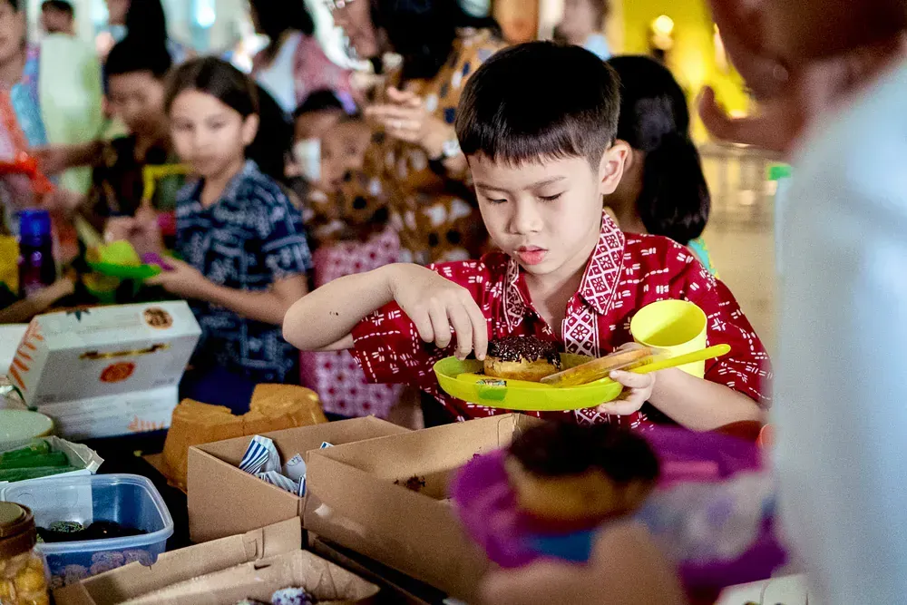 A young boy is eating a donut at a birthday party.