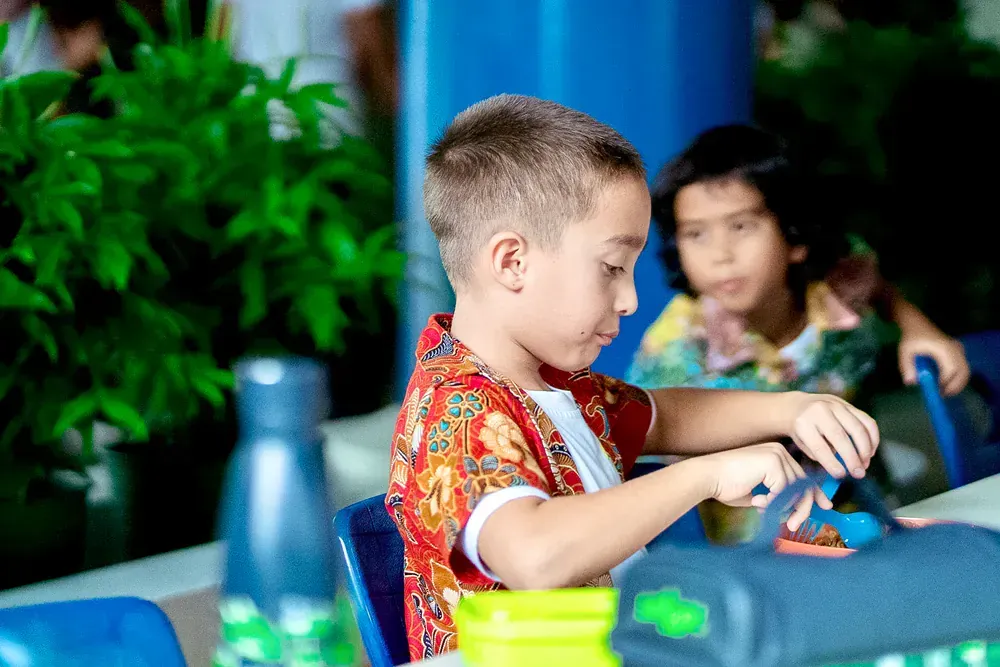 A young boy is sitting at a table playing with a toy.