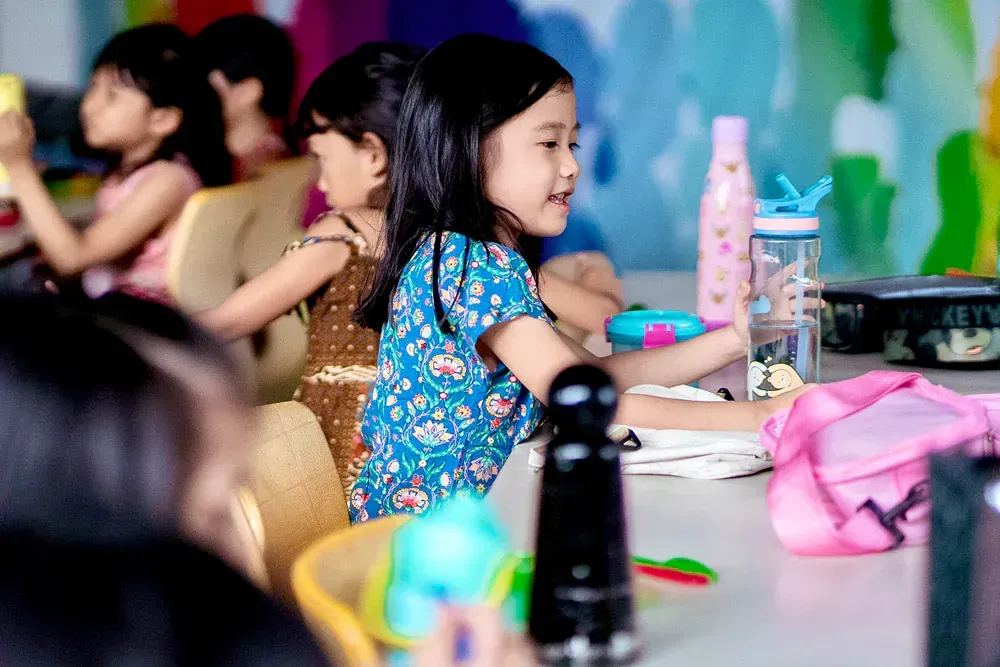 A group of young girls are sitting at a table in a classroom.