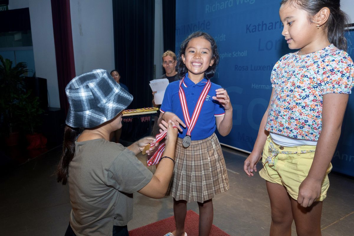 Two young girls are standing next to each other and one of them is wearing a medal.