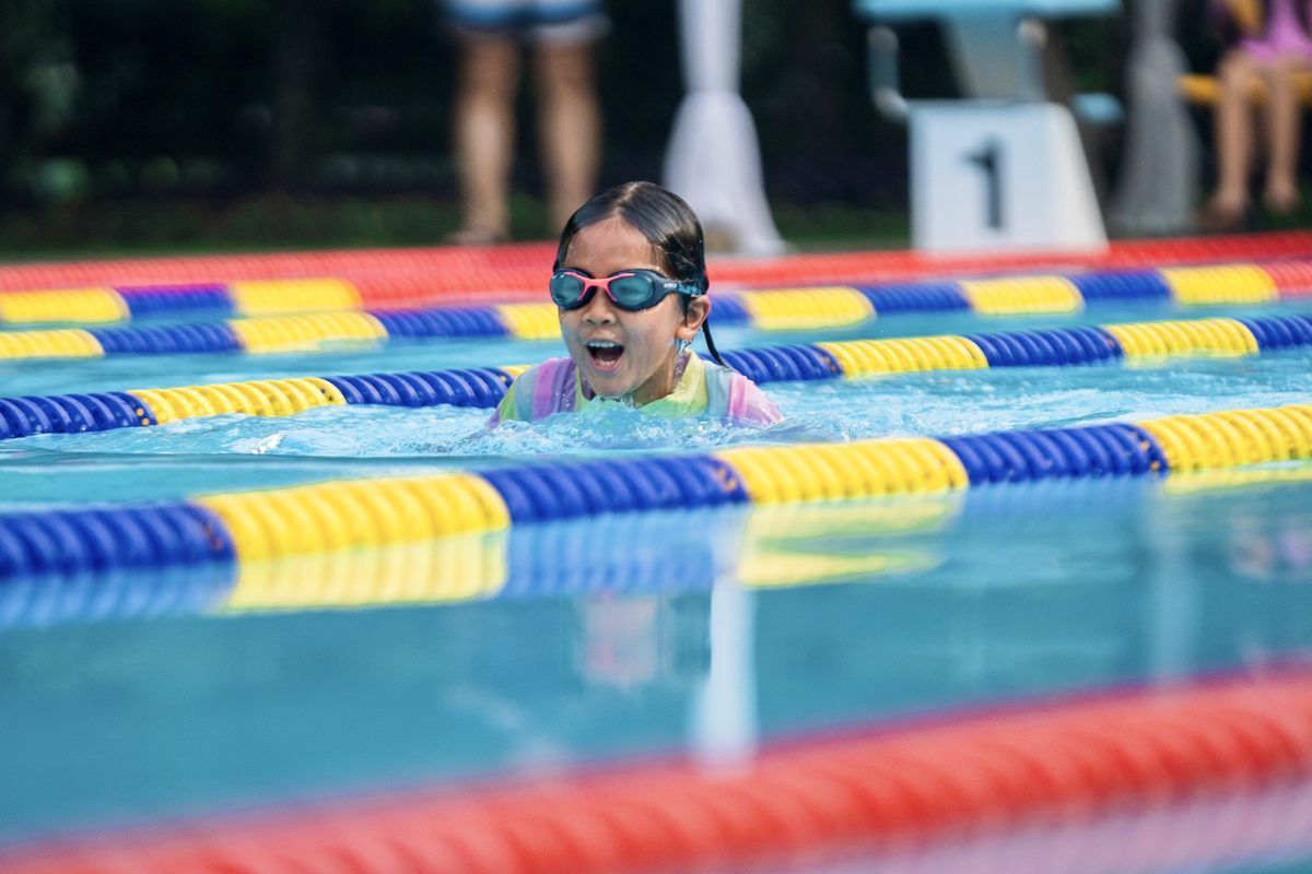 A young girl is swimming in a swimming pool.