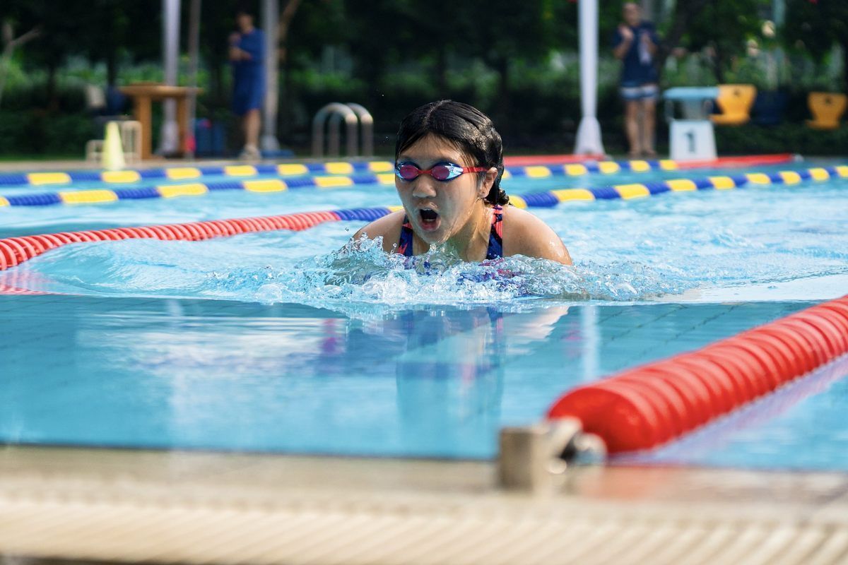 A young girl is swimming in a swimming pool.