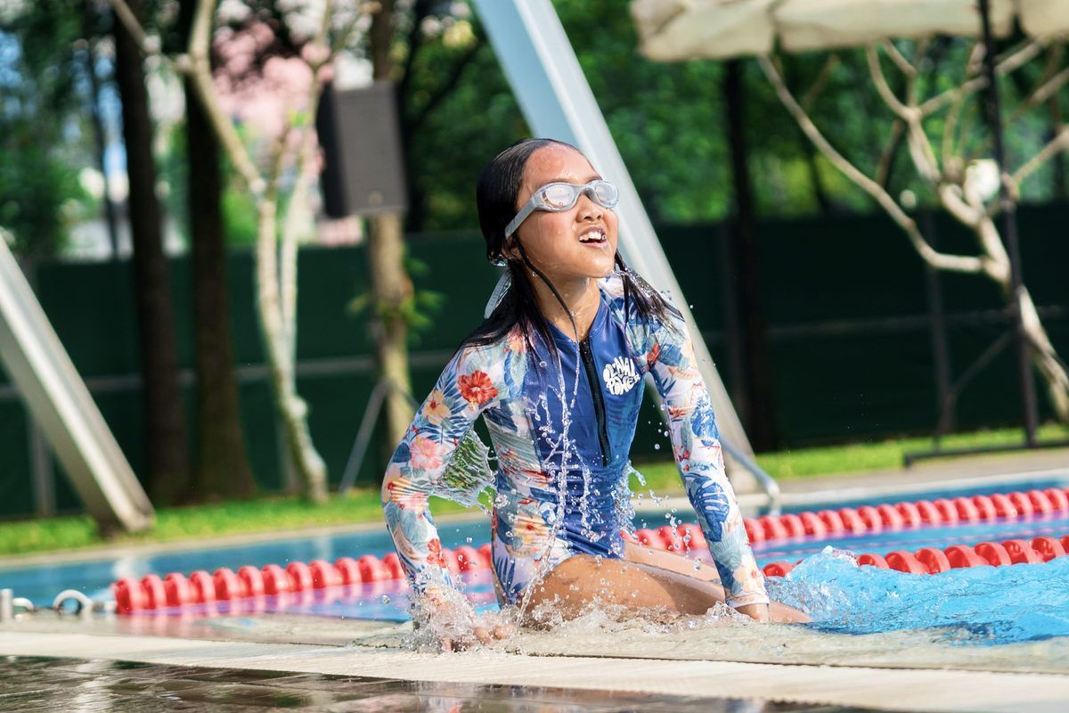 A little girl is sitting on the edge of a swimming pool.