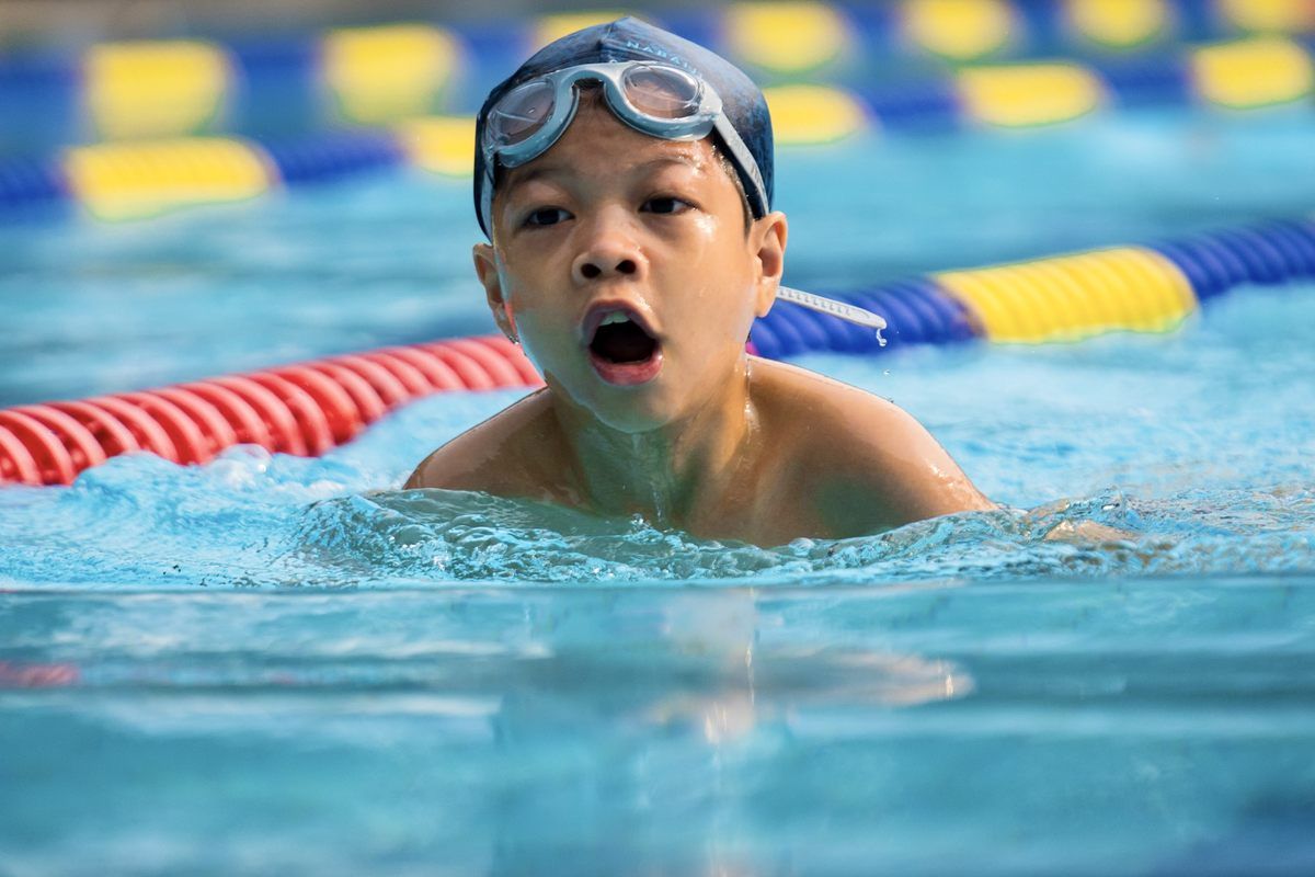 A young boy is swimming in a swimming pool.
