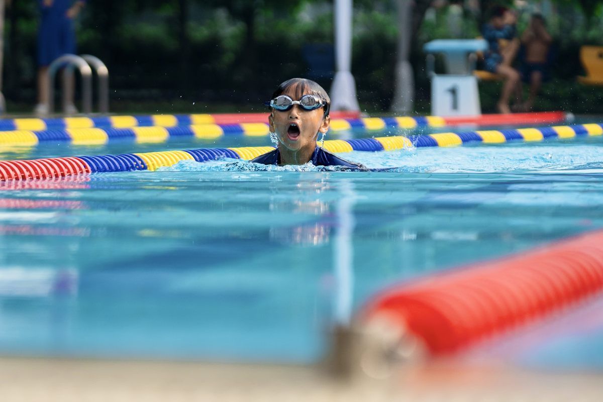 A young boy is swimming in a swimming pool.